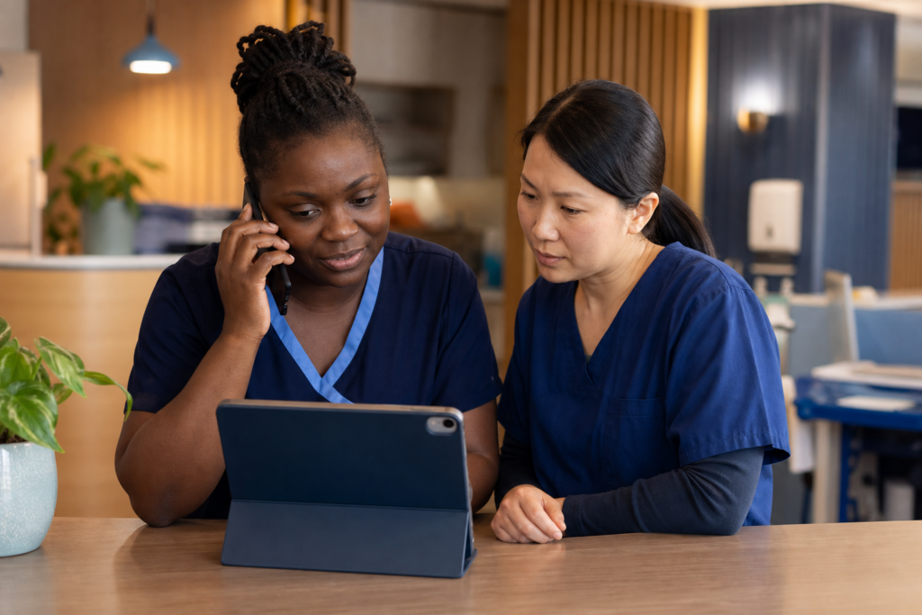 Two aged care clinicians coordinating urgent GP support by tablet and phone